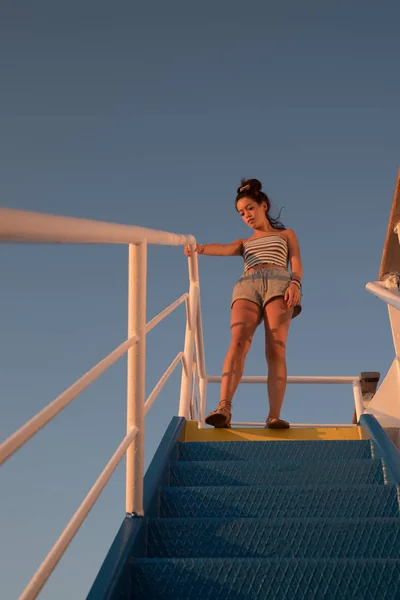 Asiático adolescente de pie en la parte superior de azul escalera con raya amarilla —  Fotos de Stock