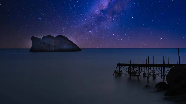 Harap olmuş, yıkık dökük bir iskelede, arka planda yıldız olan bir adada. — Stok fotoğraf