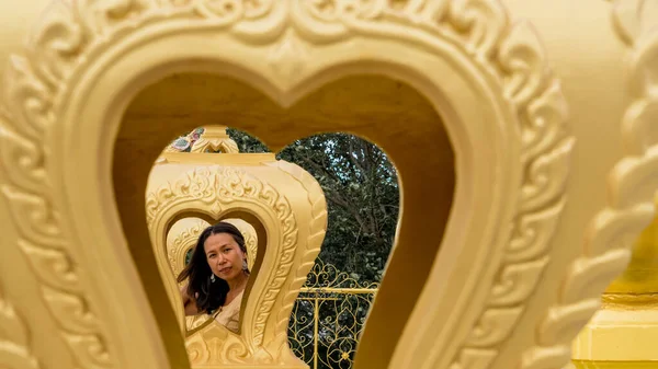 Thai woman framed by multiple gold hearts in wat in Pak Nam Pran