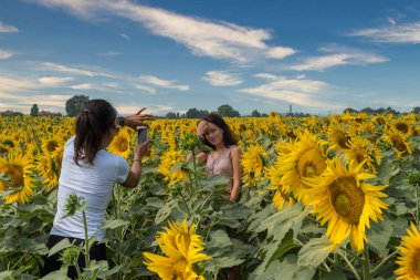Anne, Bologna İtalya 'nın dışında ayçiçekleriyle çevrili bir tarlada kızının fotoğraflarını çekiyor.