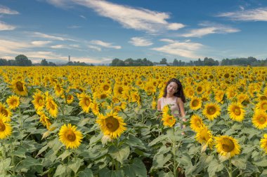 Genç kız Bologna İtalya 'nın dışında ayçiçekleriyle çevrili olarak tarlada duruyor.