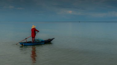 Yaşlı adam Tayland Körfezi 'ndeki sakin denizlerde smal geleneksel teknede balık tutuyor.