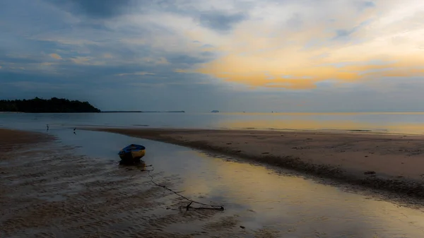 Dinghy sitting in tidal pool at beach at low tide during sunset in Pythiu on the Gulf of Thailand with anchor trailing behind