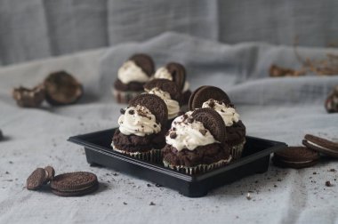 Krem şanti ve mavi-gri arka plan üzerinde çerez ile çikolata Oreo cupcakes