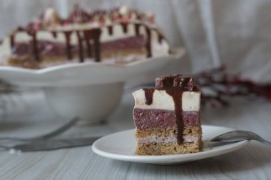 Muscovy kek ahududu lor ile ve haşhaş kek, çilek, çikolata, şekerleme ile dekore edilmiş ve bir ışık ahşap arka plan üzerinde buzlanma yumuşak