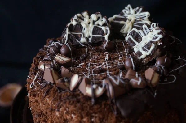 Cake with cottage cheese cream and chocolate cakes decorated with sponge cake crumbs and chocolate frosting on a dark background