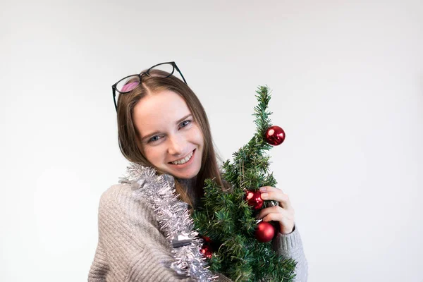 Girl with a small Christmas tree hugs and smiles — Stock Photo, Image