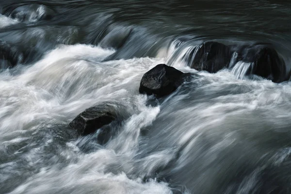 Donkere stenen in de rivier — Stockfoto