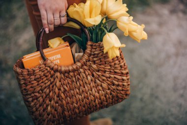 Sepet taşıyan kız elleri leylak çiçeği buketi, hasır şapka ve piknik yemeği.