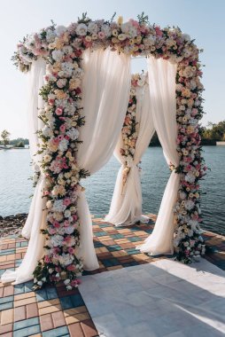 Güzel bir düğün hazırlığı. Düğün merasiminin alanı. Yuvarlak kemer, çiçeklerle süslenmiş beyaz sandalyeler, yeşillik. Sevimli, modaya uygun kırsal dekor. Festival dekorunun bir parçası, çiçek aranjmanı..