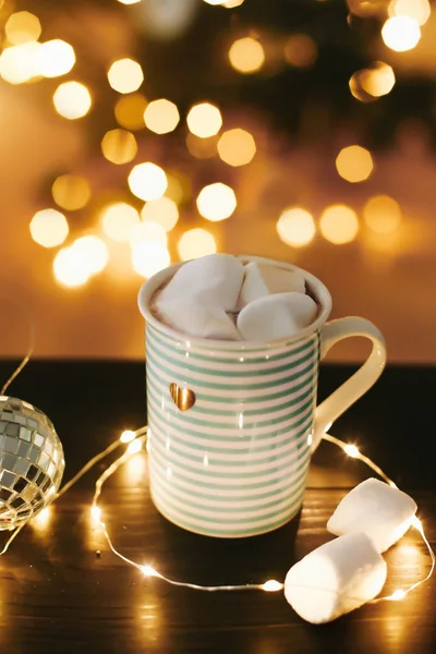 Noel kahve fincan arka planda marshmallow ile yılbaşı ışıkları ve dekorasyon. — Stok fotoğraf