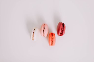 Lezzetli kurabiyeler ve beyaz arka planda çiçekler. Renkli Fransız tatlıları. 8 Mart, bahar arkaplanı. Sevgililer Günü, Kadınlar, Anneler Günü konsepti. Boşluğu kopyala, minimal biçim, düz yatış, üst görünüm.