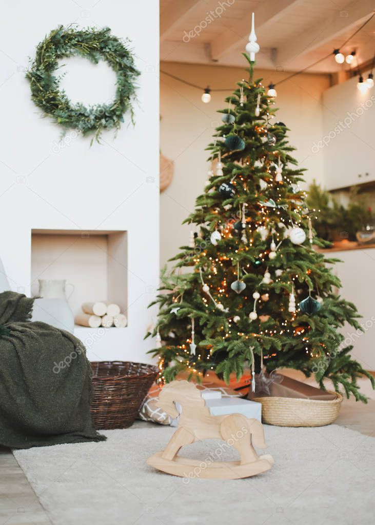 A beautiful living room decorated for Christmas. New Year interior. Decorated fir tree with garlands and balls, festive interior decorations