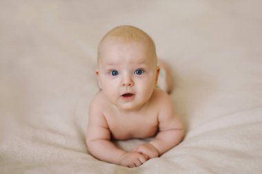 Beyaz örgü bir battaniyenin üzerinde yatan komik küçük bebek. Çocuk bezi değişimi ve cilt bakımı. 