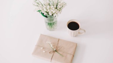 Beyaz arka planda kahve, hediye ve çiçeklerin romantik kompozisyonu. Tatil kavramı, doğum günü, Uluslararası Kadınlar Günü