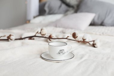 Kahve fincanı ve pamuk çiçeği. Yatakta kahvaltı. Rahat bir ev. düz, durgun hayat.