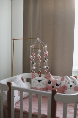 Beautiful interior of baby room with a crib. White crib with pillows and pink blanket in baby room. pastel pink bedding 