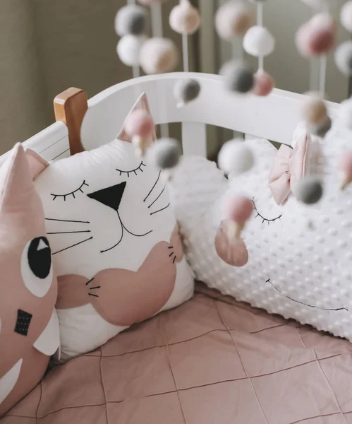 Hermoso interior de la habitación del bebé con una cuna. Cuna blanca con almohadas y manta rosa en la habitación del bebé. ropa de cama de color rosa pastel —  Fotos de Stock