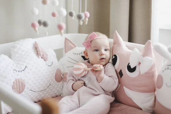 Beautiful baby girl in pink. Cute baby wearing pink body with pink flower headgear. Healthy baby in bed