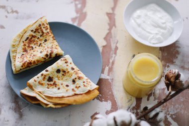 Stack of delicious homemade pancakes on plate with honey, sour cream and tea. Breakfast. Rustic style, close up top view. Flat lay