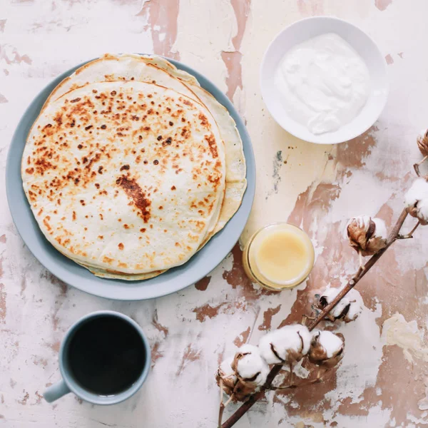 Setumpuk pancake buatan sendiri yang lezat di piring dengan madu, krim asam dan teh. Sarapan. Gaya Rustic, close up top view. Letak rata — Stok Foto