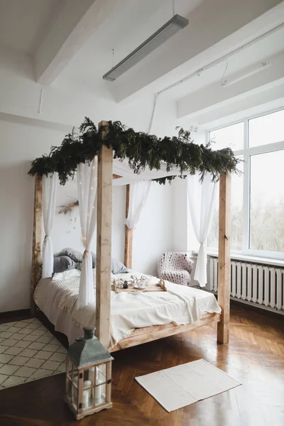 Quarto espaçoso com cama contra uma parede. Cama com dossel de madeira. Conceito de design de interiores em casa moderna. estilo escandinavo — Fotografia de Stock