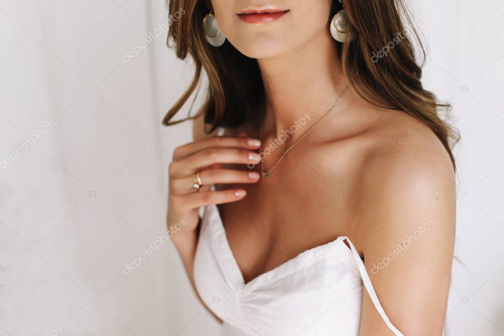 Portrait of a young beautiful woman. Bride in elegant classic wedding dress. Morning of the bride. Wedding preparations.