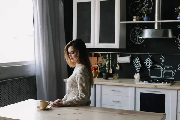 Uma rapariga a beber café na cozinha em casa. Jovem segurando xícara de café. Uma rapariga a beber bebidas no café. Bom dia. . — Fotografia de Stock