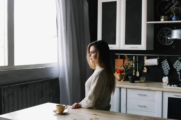 Uma rapariga a beber café na cozinha em casa. Jovem segurando xícara de café. Uma rapariga a beber bebidas no café. Bom dia. . — Fotografia de Stock