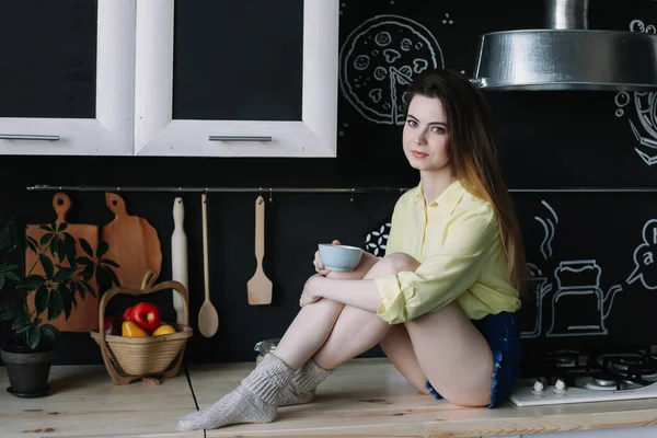 Uma rapariga a beber café na cozinha em casa. Jovem segurando xícara de café. Uma rapariga a beber bebidas no café. Bom dia. . — Fotografia de Stock