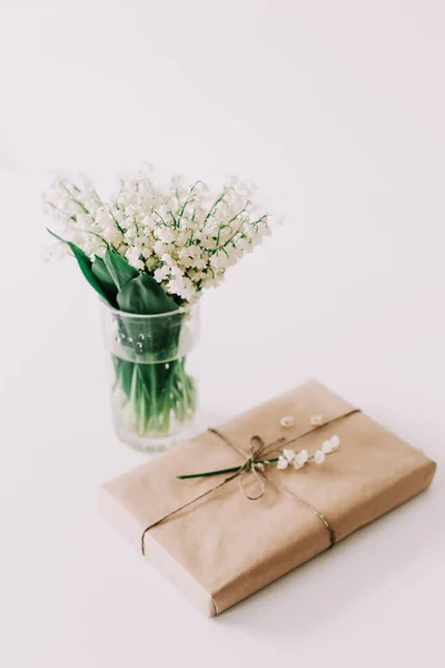 Pretty gift box with a bouquet of lilies of the valley on white background. Concept of holiday, birthday, Womens Day. flat lay — Stock Photo, Image