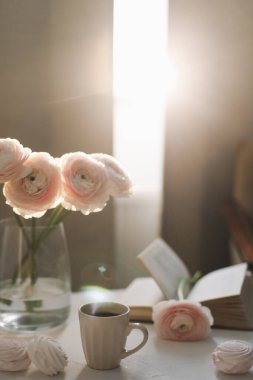 Bahar hala hayattır. Kahve fincanı, çiçekler, kitap ve şekerleme. Sıcak ev dekorasyonu. Tatil kavramı, doğum günü. Dişi düz uzanış