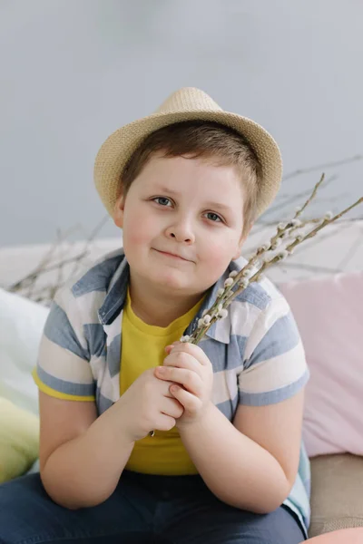 Närbild porträtt av en pojke i en hatt som håller torra pilkvistar. Begreppet vår och påsk. — Stockfoto