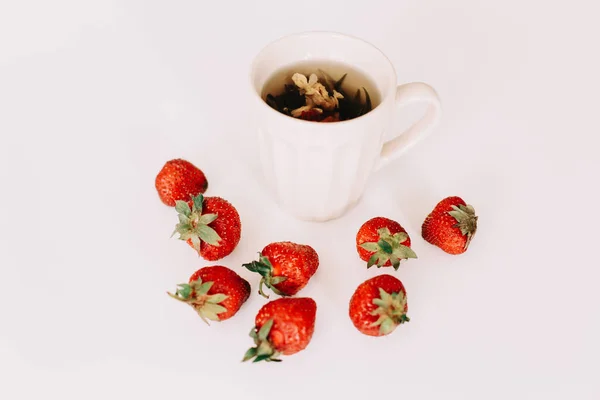 Green tea with strawberries on a white background. Flat lay, top view