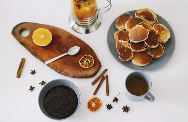 Pancake mewah dan teko teh dengan rempah-rempah, secangkir teh dengan jeruk, kayu manis, adas. Sarapan lezat dengan latar belakang putih. Selamat pagi. — Stok Foto