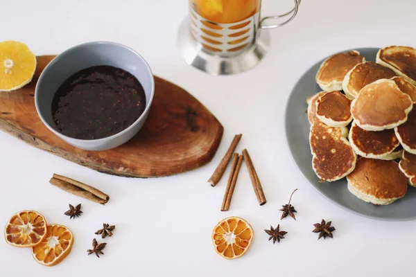 Lush pancakes and teapot with spices, cup of tea with orange, cinnamon, anise. Tasty breakfast on white background. Good morning — Stock Photo, Image