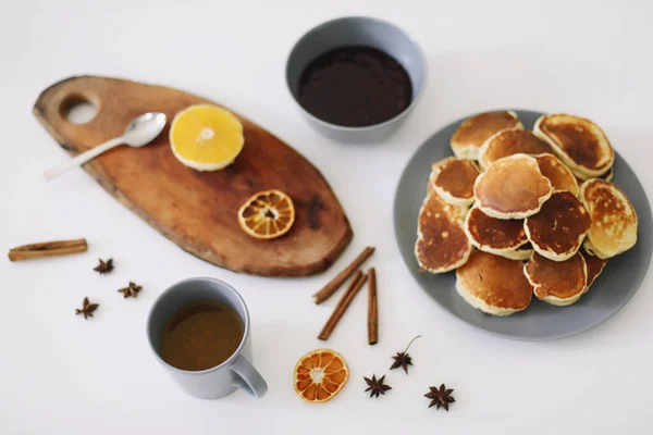 Pancake mewah dan teko teh dengan rempah-rempah, secangkir teh dengan jeruk, kayu manis, adas. Sarapan lezat dengan latar belakang putih. Selamat pagi. — Stok Foto