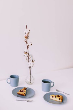 Tabakta bir parça turta ve beyaz masada bir fincan çay. Çay ve pastayla kahvaltı. Yemek fotoğrafçılığı. Masanın üstündeki fotoğraf. Çay zamanı.