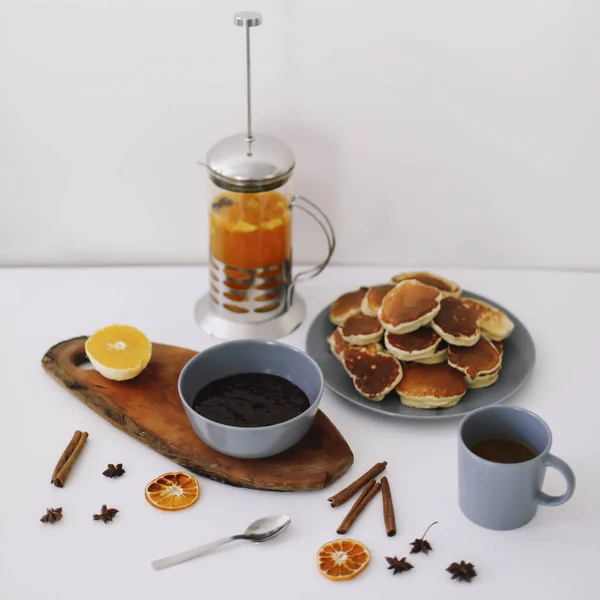 Üppige Pfannkuchen und Teekanne mit Gewürzen, Tasse Tee mit Orange, Zimt, Anis. Leckeres Frühstück auf weißem Hintergrund. Guten Morgen — Stockfoto