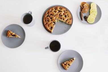 Tabakta bir parça turta ve beyaz masada bir fincan çay. Çay ve pastayla kahvaltı. Yemek fotoğrafçılığı. Masanın üstündeki fotoğraf. Çay zamanı.