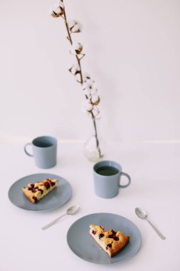 Tabakta bir parça turta ve beyaz masada bir fincan çay. Çay ve pastayla kahvaltı. Yemek fotoğrafçılığı. Masanın üstündeki fotoğraf. Çay zamanı.