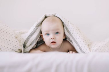 Bebek yatakta dinleniyor. Beyaz güneşli yatak odasındaki bebek. Çocuklar için çocuk odası. Çocuklar için tekstil ve yatak. 
