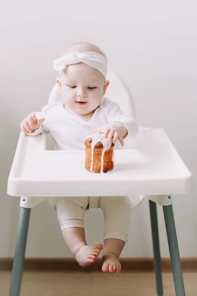 Lindo bebé en una silla de bebé disfruta comiendo el pastel con sus manos. Bebé sentado en la silla alta. Feliz cumpleaños concepto . — Foto de Stock