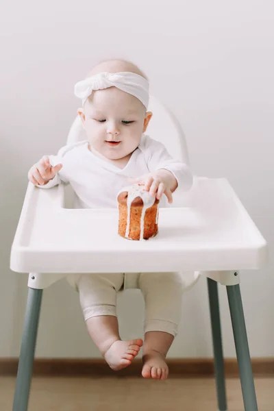 Bebek koltuğundaki şirin bebek elleriyle pasta yemekten zevk alıyor. Bebek sandalyede oturuyor. Mutlu yıllar..