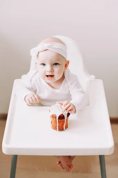 Lindo bebé en una silla de bebé disfruta comiendo el pastel con sus manos. Bebé sentado en la silla alta. Feliz cumpleaños concepto . — Foto de Stock