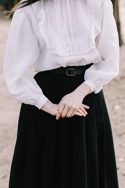 Студентка или студентка в форме. Руки девушки крупным планом. Девушка в чёрной юбке и белой блузке — стоковое фото