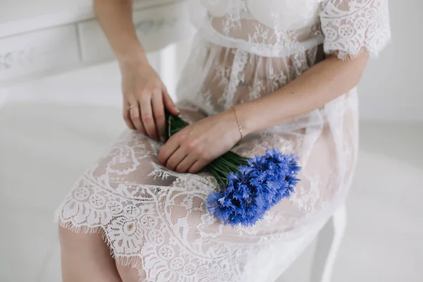 Una ragazza con una camicia bianca tiene un mazzo di fiori selvatici. Sposa in lingerie contenente bouquet da sposa. Mattina riunioni di nozze — Foto Stock