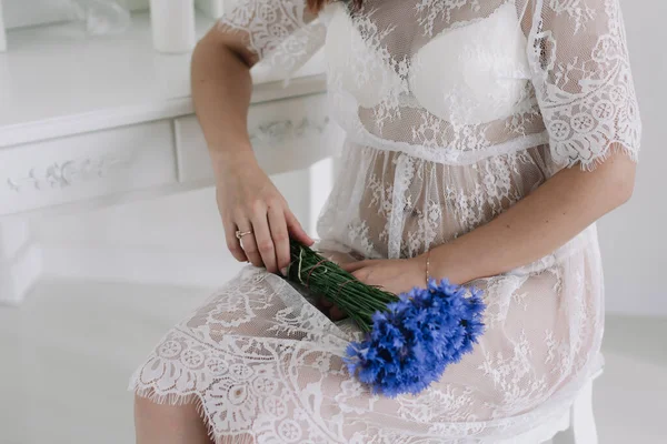 Uma menina de camisa branca segura um buquê de flores silvestres. Noiva em lingerie segurando buquê de casamento. Reuniões de casamento da manhã — Fotografia de Stock