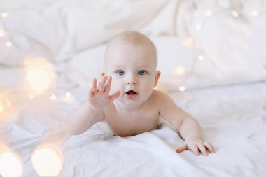 Karnını doyuran küçük bir çocuk. Sevimli bebek beyaz yatak odasında emeklemeyi öğreniyor. Yatakta yatan sevimli komik bebek.. 
