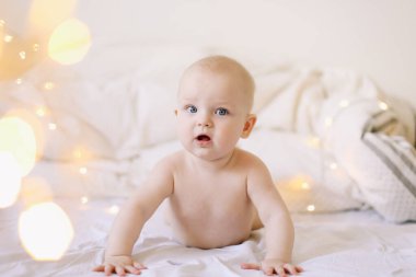 Karnını doyuran küçük bir çocuk. Sevimli bebek beyaz yatak odasında emeklemeyi öğreniyor. Yatakta yatan sevimli komik bebek.. 
